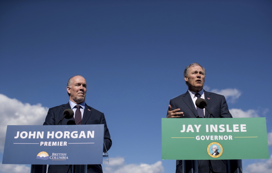 British Columbia Premier John Horgan, left, listens as Washington Gov. Jay Inslee speaks Friday in Vancouver, B.C., during a news conference about high-speed rail.