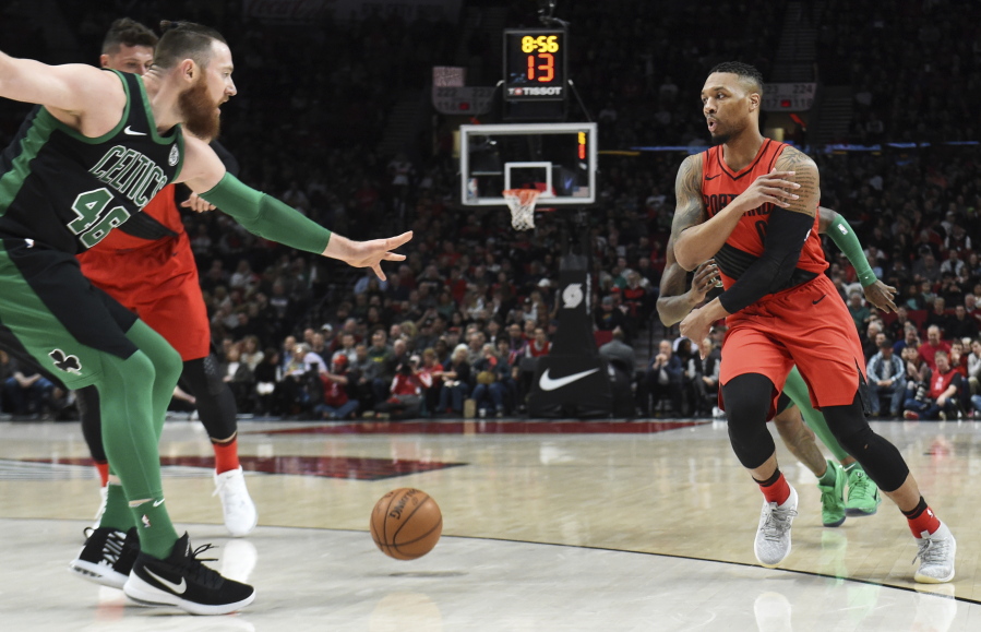 Portland Trail Blazers guard Damian Lillard passes the ball on Boston Celtics center Aron Baynes during the first half of an NBA basketball game in Portland, Ore., Friday, March 23, 2018.