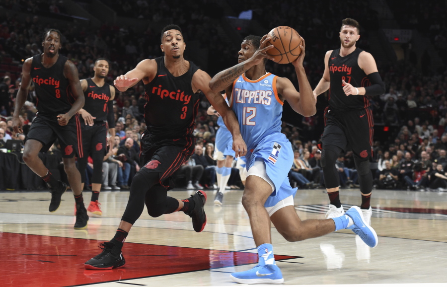 Los Angeles Clippers guard Tyrone Wallace, right, drives to the basket on Portland Trail Blazers guard CJ McCollum, left, during the first half of an NBA basketball game in Portland, Ore., on Friday, March 30, 2018.