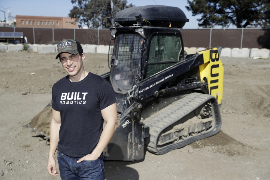 Built Robotics CEO Noah Ready-Campbell poses for a picture in front of the company’s autonomous track loader Wednesday, Feb. 21, 2018, in San Francisco. Backed by Silicon Valley money, tech startups are developing self-driving bulldozers, drones to inspect work sites and robot bricklayers that can lay bricks faster than human and work without lunch breaks.