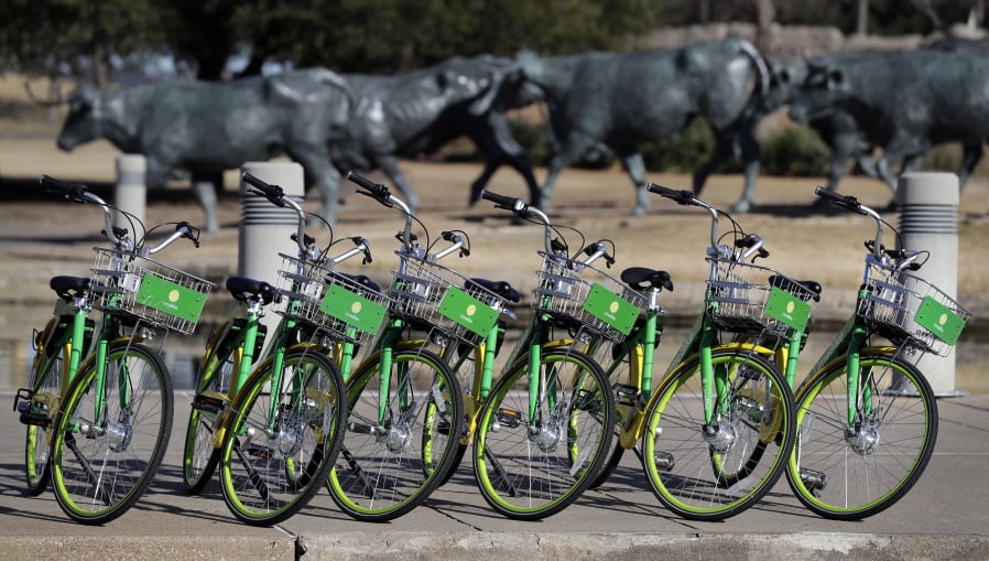 In this Feb. 8, 2018 photo, shared bikes ready to be used are lined up on a sidewalk by a popular tourist destination in Dallas. Shared bikes that can be left wherever the rider ends up are helping more people get access to the mode of transportation that reduces car traffic and increases exercise. But the dockless bikes are also producing some chaos with discarded bikes cluttering public spaces, blocking sidewalks and even placed in trees and lakes. Over the last year, startup companies have brought the bikes that don’t require docking stations into city after city in the U.S.