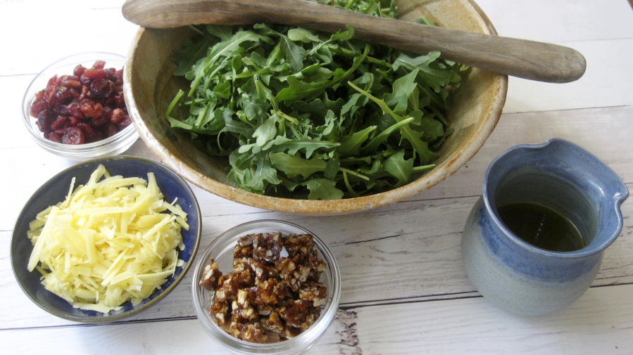 Components of an arugula salad with spicy pecan praline, dried cranberries and aged gouda in New York. Each of the ingredients brings its own unique taste and texture to the mix, but the standout is the praline.