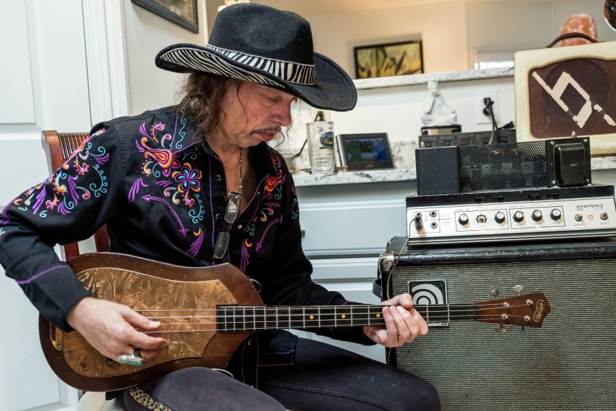 In this February 2018 photo, Randy Hansen plays an Audiovox Model 736 electric bass guitar made by Seattle builder Paul Tutmarc in the mid-1930s, in the Seattle kitchen of Bev and Dale McKnight, who bought the guitar from Tutmarc decades ago and are selling it on eBay.