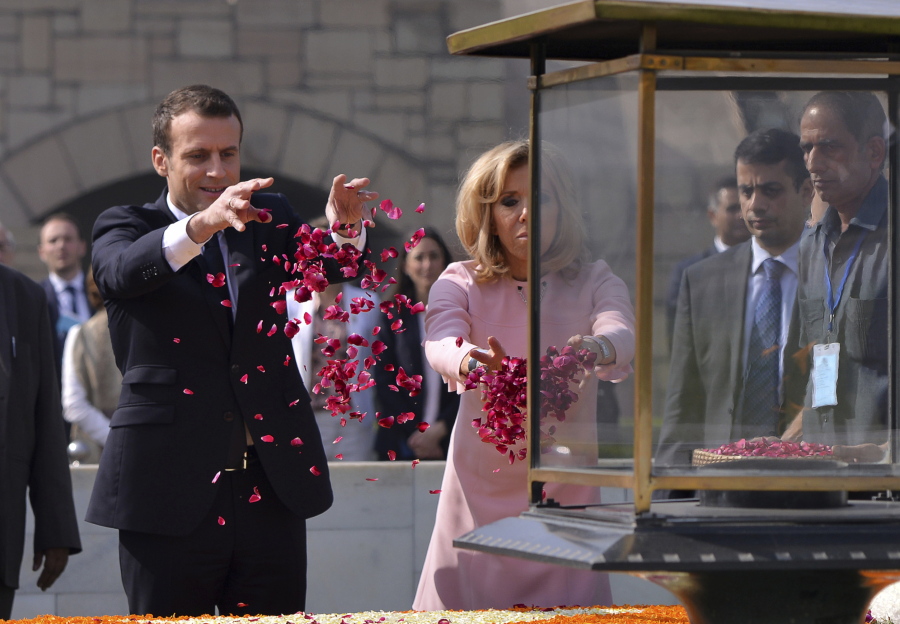 French President Emmanuel Macron, left, and his wife, Brigitte, offer floral tributes Saturday at Rajghat, Mahatma Gandhi memorial, in New Delhi, India.