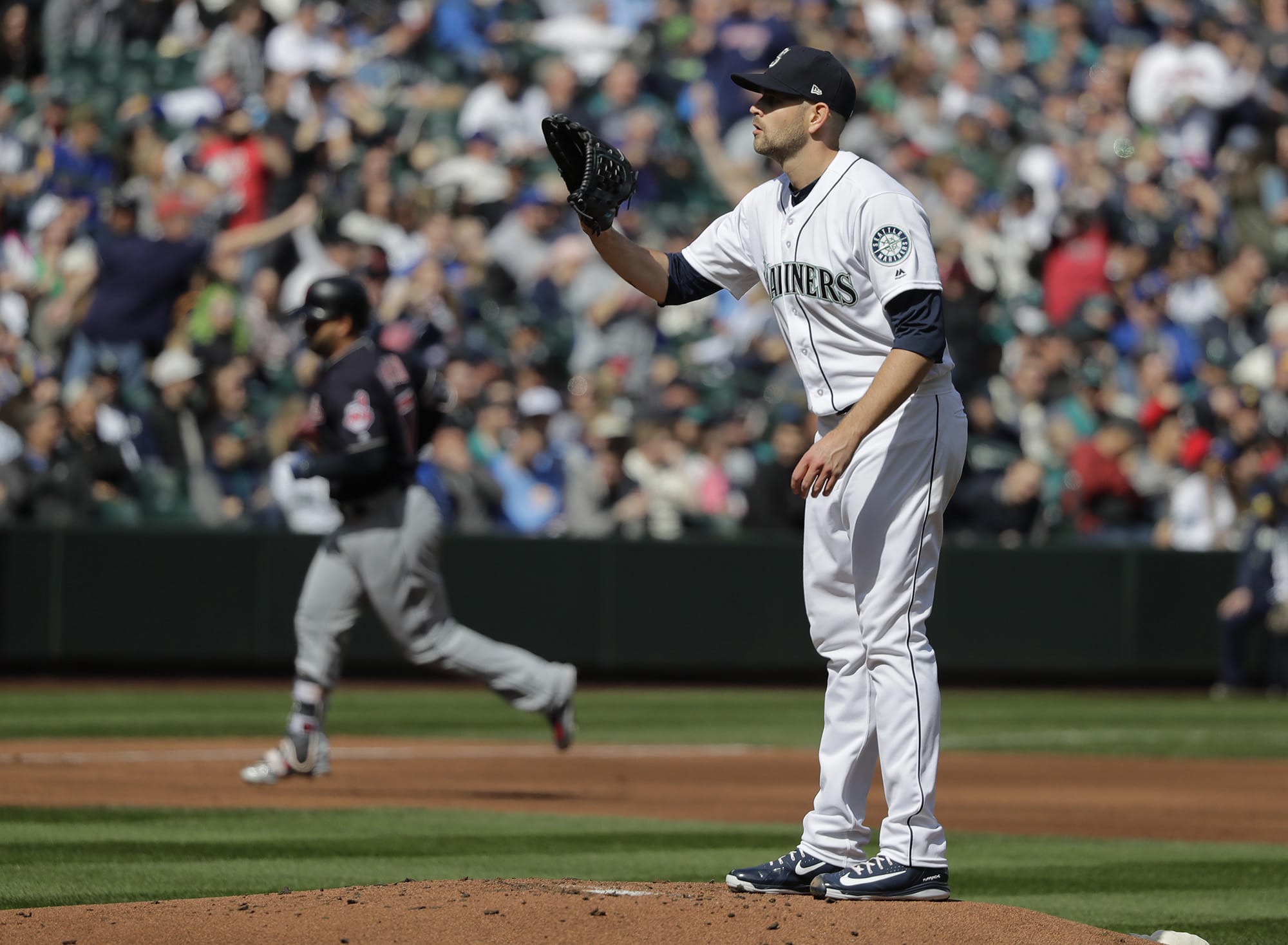 Seattle Mariners starting pitcher James Paxton, right, stands on the mound as Cleveland Indians' Yonder Alonso, left, rounds the bases after Alonso hit a grand slam during the first inning of a baseball game, Saturday, March 31, 2018, in Seattle. (AP Photo/Ted S.