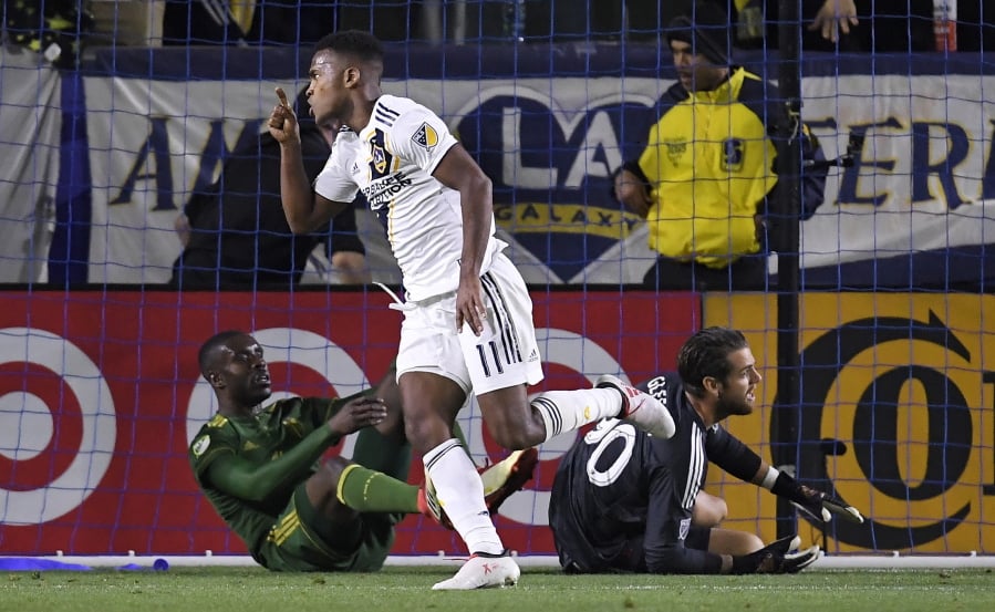 Los Angeles Galaxy forward Ola Kamara, center, celebrates his goal as Portland Timbers defender Larrys Mabiala, left, and goalkeeper Jake Gleeson lie on the ground during the first half of a Major League Soccer game, Sunday, March 4, 2018, in Carson, Calif. (AP Photo/Mark J.