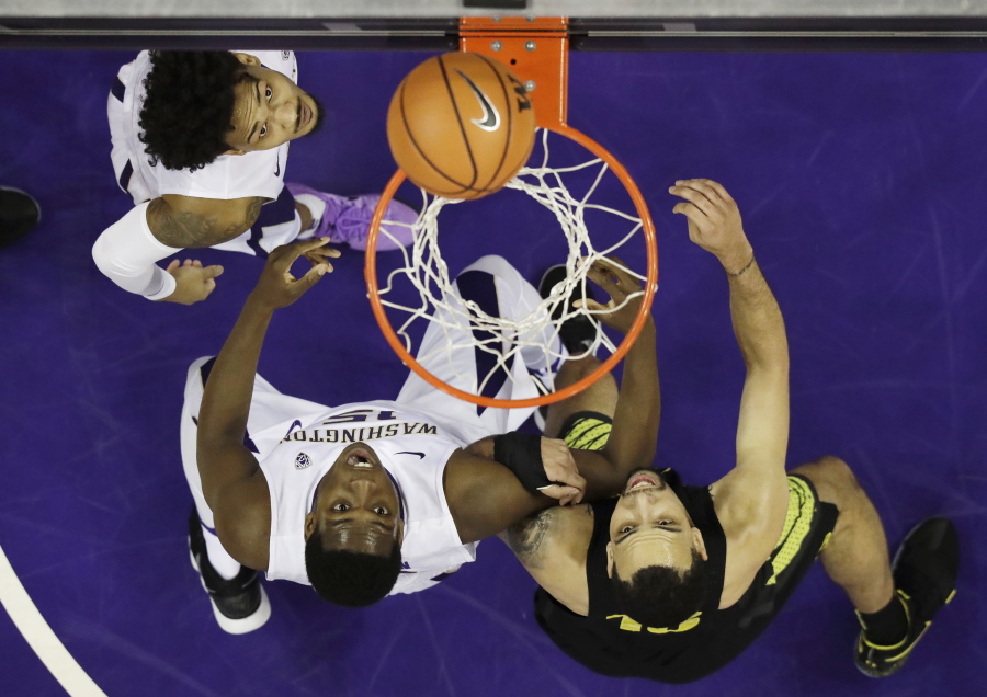 Washington’s David Crisp, upper left, Noah Dickerson, lower left, and Oregon’s Paul White, right, watch as the ball goes through the hoop for a Washington basket in the first half of an NCAA college basketball game, Saturday, March 3, 2018, in Seattle. (AP Photo/Ted S.