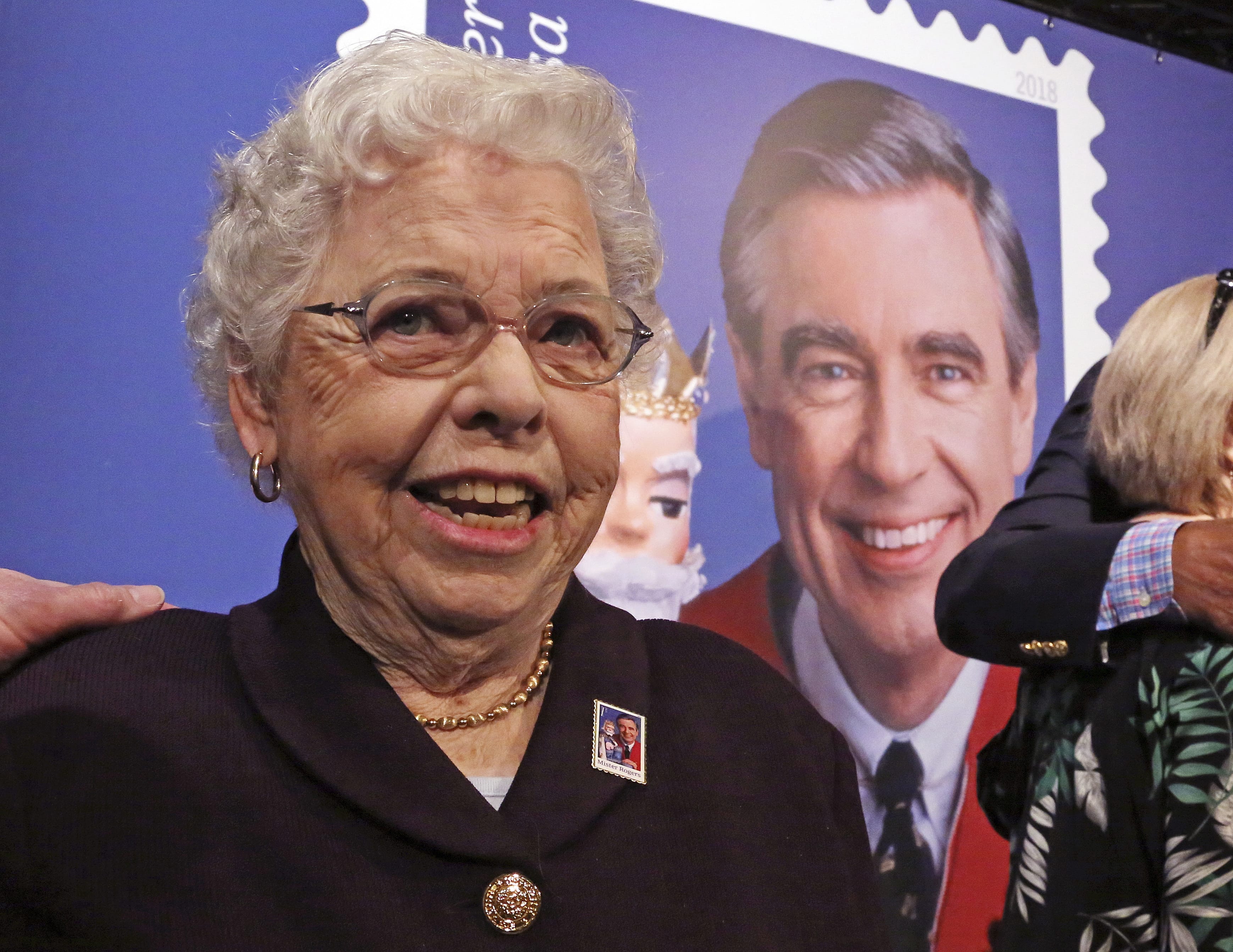 Joanne Rogers, widow of Fred Rogers, visits with friends in front of a giant Mister Rogers Forever Stamp following the first-day-of-issue dedication in WQED's Fred Rogers Studio in Pittsburgh, Friday, March 23, 2018. (AP Photo/Gene J.