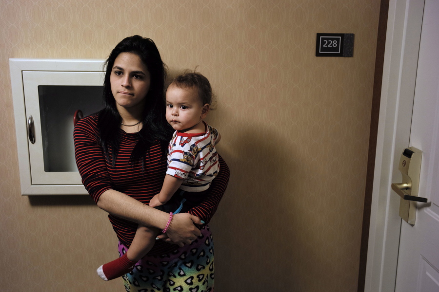 In this Tuesday, Feb. 27, 2018 photo, Jesenia Flores holds her son Jose, both of Aibonito, Puerto Rico, as they wait to enter her mother-in-law’s hotel room, in Dedham, Mass. Nearly six months after Hurricane Maria, thousands of Puerto Ricans are still staying in hotels. It’s frustrating “to be cooped up here without knowing what will happen to us,” the 19-year-old mother said.