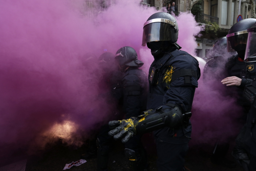 Catalan Mossos d’Esquadra regional police officers stand amid smoke from a smoke bomb Sunday during clashes with pro-independence supporters trying to reach the Spanish government office in Barcelona, Spain. Grassroots groups both for and against Catalan secession called for protests Sunday in Barcelona after Carles Puigdemont, the fugitive ex-leader of Catalonia and ardent separatist, was arrested Sunday by German police on an international warrant.