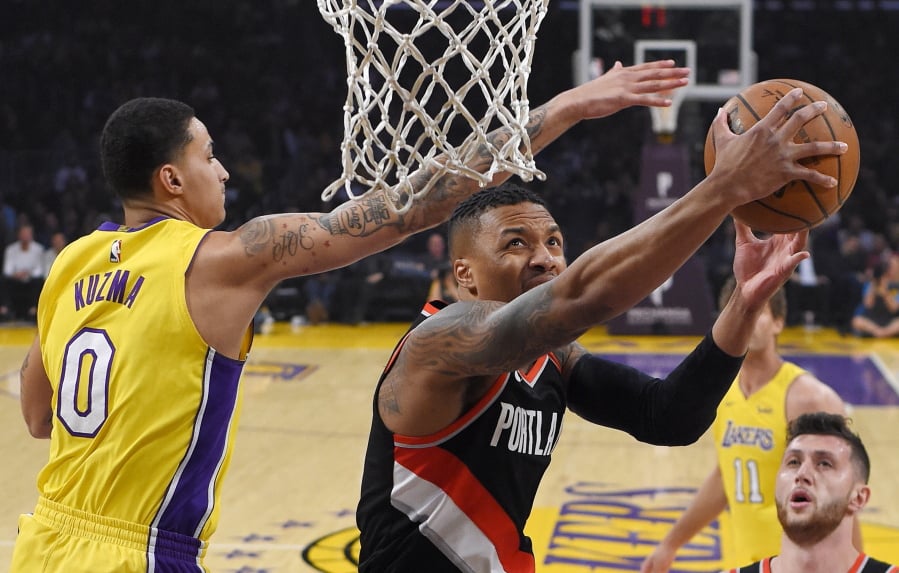 Portland Trail Blazers guard Damian Lillard, center, shoots as Los Angeles Lakers forward Kyle Kuzma (0) defends during the first half of an NBA basketball game, Monday, March 5, 2018, in Los Angeles. (AP Photo/Mark J.