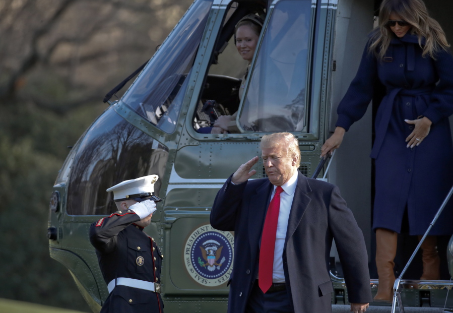 President Donald Trump salutes Monday as he steps off Marine One, accompanied by first lady Melania Trump, on the South Lawn of the White House. Trump is returning from a trip to New Hampshire.