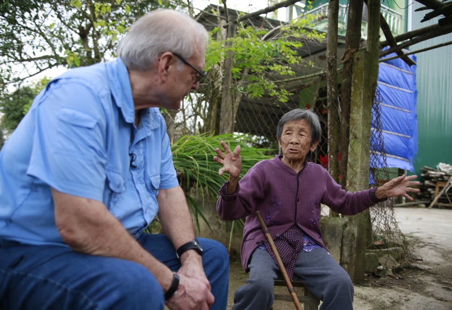 In this Thursday, March 15, 2018 photo, U.S. army photographer Ron Haeberle, left, speaks to Do Thi Chi, a survivor of My Lai massacre in My Lai, Vietnam. More than a thousand people are marking 50th anniversary of the My Lai massacre, using the event to talk of peace and cooperation instead of hatred.