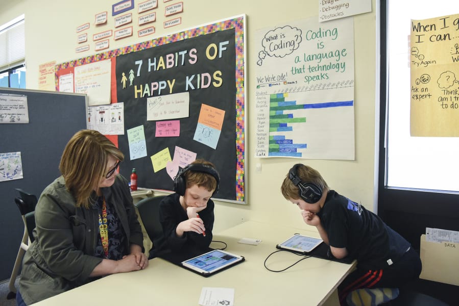 Felida Elementary School special education teacher Deb Lobdell, left, helps second-grader Carsten Edwards, 8, and first-grader, Scott Traux, 6, while they solve puzzles and design backgrounds on Code.org during their special education class March 29 at Felida Elementary School.