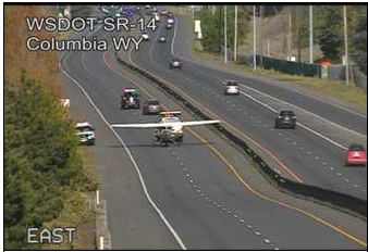 A Washington Department of Transportation traffic cam shows emergency personnel working to remove a single-engine aircraft that had landed on state Highway 14 during a training flight.