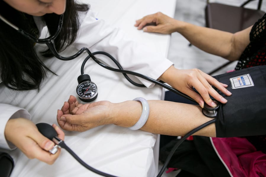 Ei Yupar Win, left, measures a patient’s blood pressure in the general medical screening area May 10, 2015, during the Hsi Lai Temple Health Fair in Hacienda Heights, Calif.