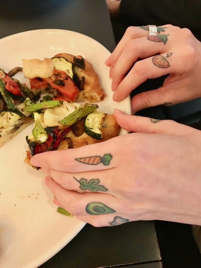Jenelle York’s fruit and veggie tattoos are on display while she eats a roasted vegetable flatbread at Bleu Door Bakery.