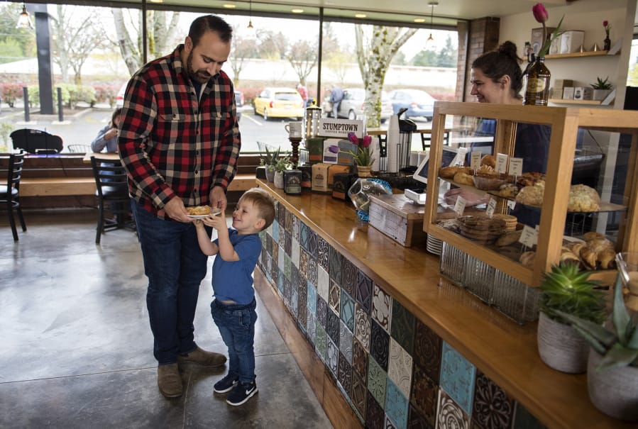 After closing up shop on Devine Road in June, River Maiden Artisan Coffee is back up and running at a new location — 5301 E. Mill Plain Blvd. — in Vancouver. Adam Hendrix of Vancouver, left, and his son, Cal, 3, stop by the new shop for a treat on Monday morning.
