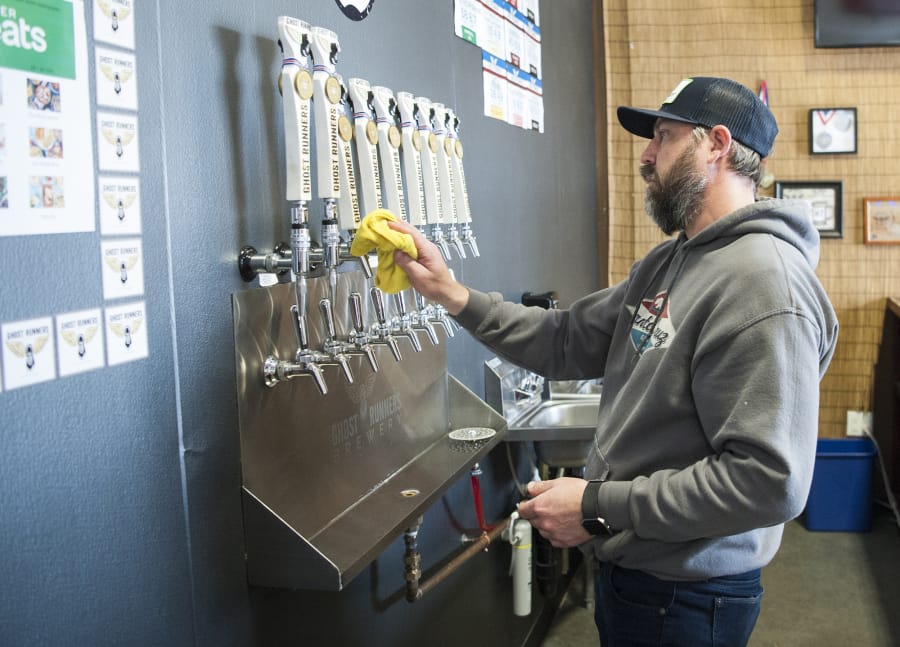 Jeff Seibel, co-owner of Ghost Runners Brewery, cleans up at the brewery’s taproom Thursday afternoon. The Vancouver brewery will keep its taproom after reaching a settlement with a former investor.