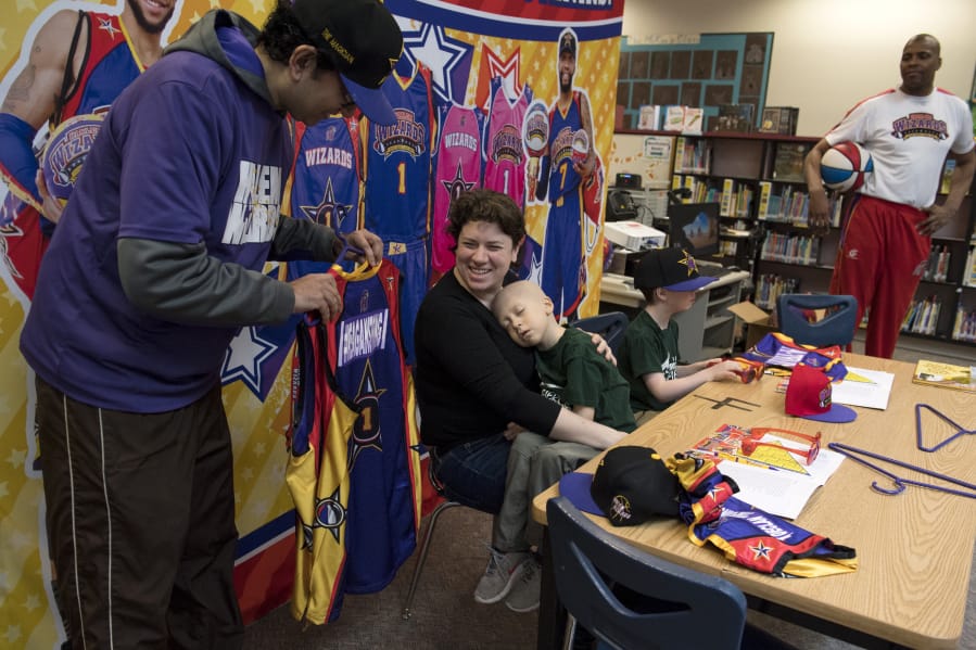Manu Iyer, with the Harlem Wizards, presents Lauren Reagan with team jersey for her and her husband, Francis Reagan. Their twin sons, Declan and Adrian, were signed by the team during a ceremony Wednesday morning. Declan recently started hospice care after a two year fight with leukemia.