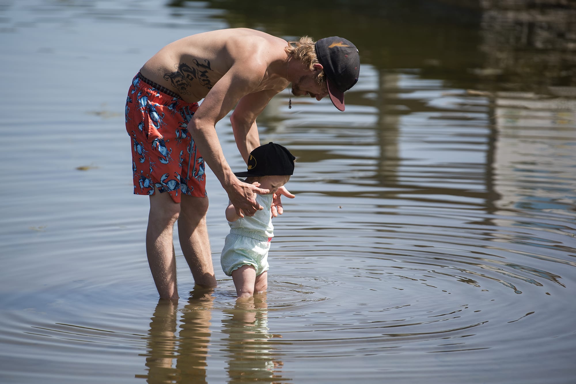 Michael Gile of Vancouver, left, and Hannah Forslund, not pictured, play with their daughter Lily, 1, right, at the edge of Klineline Pond in Vancouver on April 25.