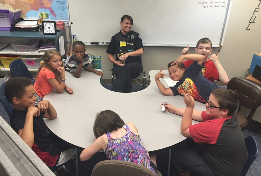 Vancouver police officer Julie Ballou sits with a group of fifth-graders at Orchards Elementary School. As part of her volunteering work with the Police Activities League, Ballou “adopted” the class, and meets with them regularly.