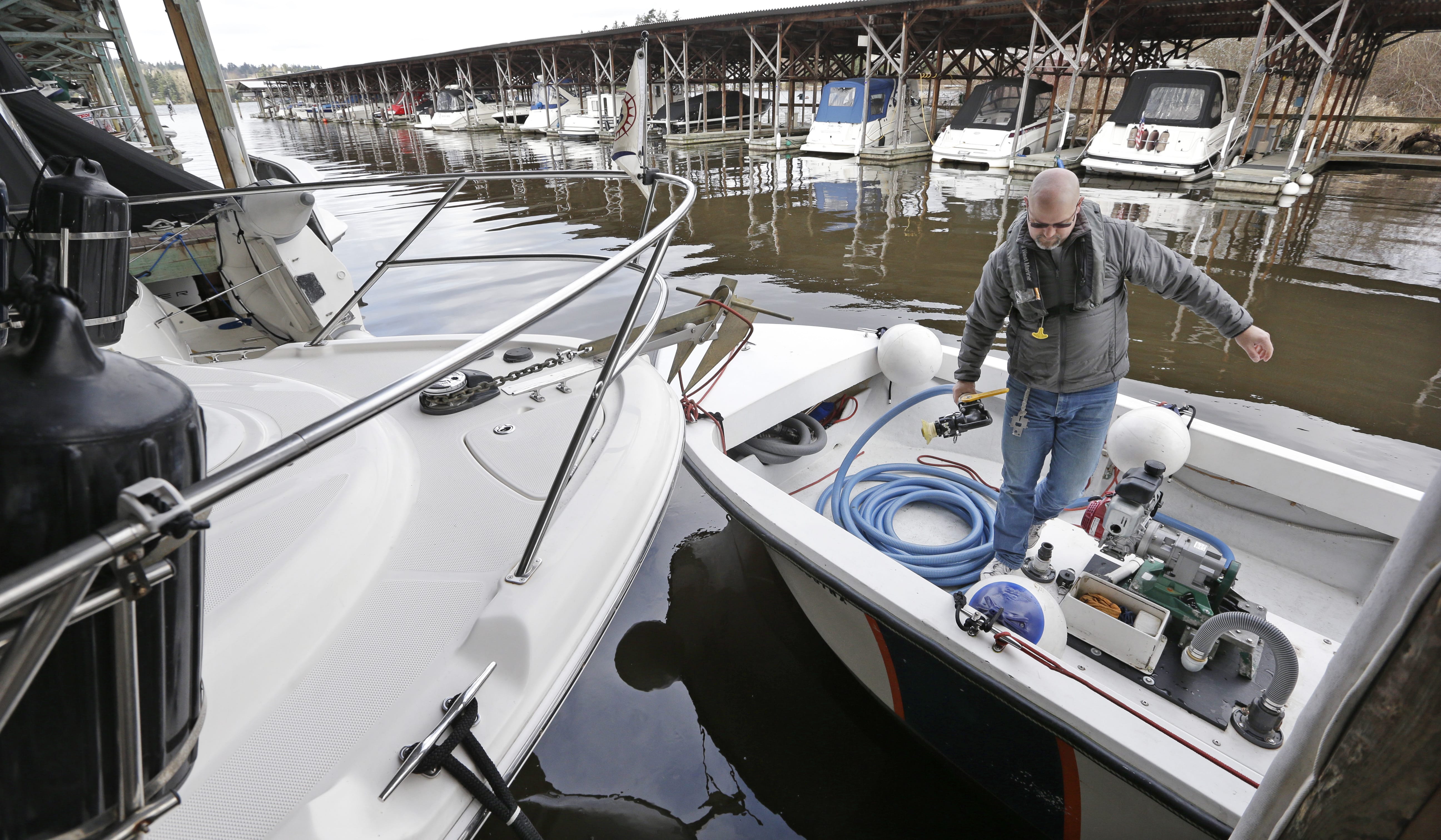 FILE - In this Feb. 19, 2014, file photo, Terry Durfee prepares his equipment to pump sewage out of a holding tank of a pleasure boat moored in Lake Washington and into his smaller boat for transport to a waste facility, in Bellevue, Wash. Recreational and commercial vessels will not be able to release treated or untreated sewage into Puget Sound waters under new rules approved by the state. The Department of Ecology on Monday, April 9, 2018, officially designated a new "no discharge zone" in Puget Sound to improve water quality and protect shellfish beds and swimming beaches from harmful bacteria. The new rules begin May 10.