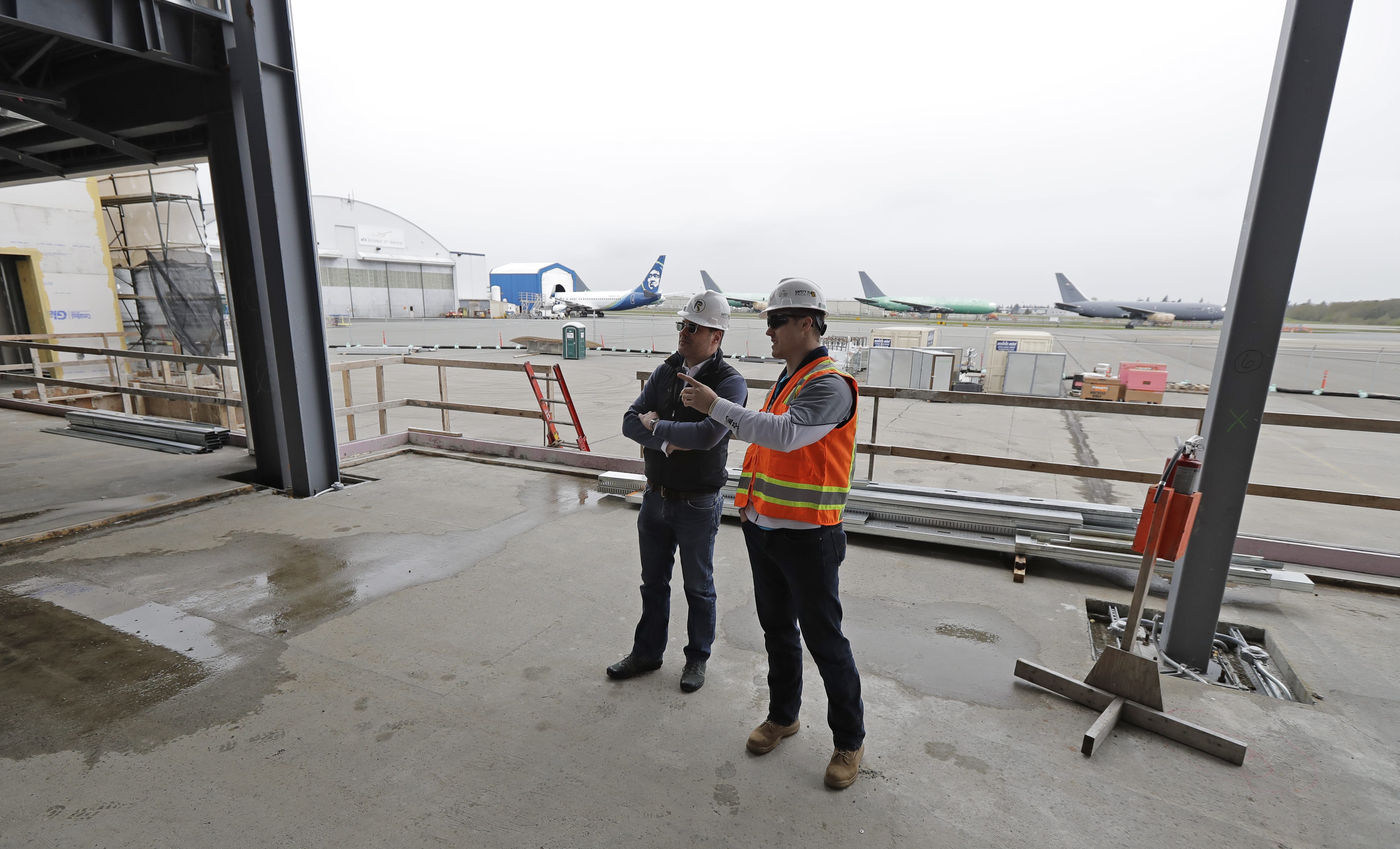 In this April 11, 2018 photo, Brett Smith, CEO of Propeller Airports, left, talks with project engineer Todd Raynes, right, inside the privately-run commercial U.S. airport terminal Smith's company is building at Paine Field in Everett, Wash. Propeller Airports sold $50 million in bonds earlier this year to finance the construction, according to data obtained by The Associated Press. The terminal has commitments from Alaska Airlines, Southwest Airlines and United Airlines for up to 24 daily flights, mostly to destinations in the West and Midwest. (AP Photo/Ted S.