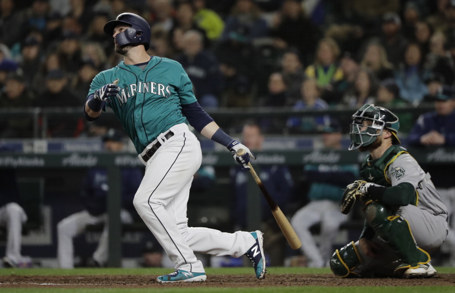 Seattle Mariners’ Mitch Haniger watches his three-run home run in front of Oakland Athletics catcher Jonathan Lucroy during the seventh inning of a baseball game, Friday, April 13, 2018, in Seattle. (AP Photo/Ted S.