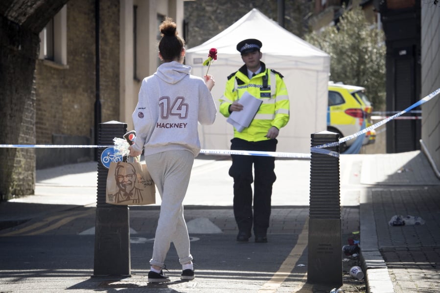 A woman carries a flower to a crime scene in Link Street, Hackney, east London, Thursday April 5, 2018. This week, 18-year-old Israel Ogunsola became London’s 53rd murder victim of 2018. The British capital is being shaken by a spike in deadly violence, much of it involving young people caught up in gang feuds.