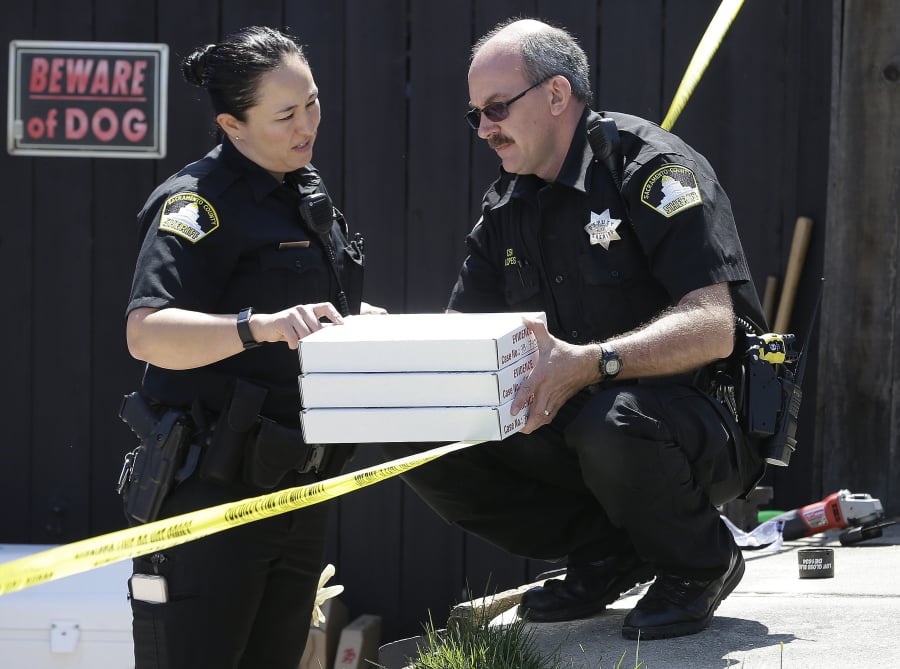 T. Abbott, left, and John Lopes, right, from the Sacramento County Sheriff’s crime scene investigation office, conference Thursday about boxes of evidence gathered from the home of murder suspect Joseph DeAngelo in Citrus Heights, Calif.