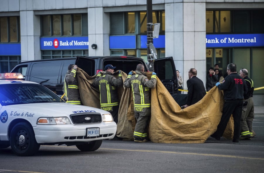 Officials carry a body into a vehicle after a van mounted a sidewalk crashing into pedestrians in Toronto on Monday. The rented van jumped onto the crowded sidewalk Monday, killing and injuring people before the driver fled and was quickly arrested in a confrontation with police, Canadian authorities said.