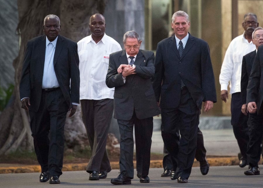 FILE - In this Jan. 28, 2018 file photo, Cuba’s President Raul Castro looks at his watch as he walks with Cuba’s Vice President Miguel Diaz-Canel Bermudez, right, and National Assembly of People’s Power President Esteban Lazo Hernandez, left, to the unveiling of a replica of a statue of Cuba’s independence hero Jose Marti in Havana, Cuba. The greatest immediate challenge for Castro’s expected successor, 57-year-old Diaz-Canel, is unwinding a byzantine dual-currency system featuring one type of Cuban peso worth 4 cents and another that’s nearly a dollar.