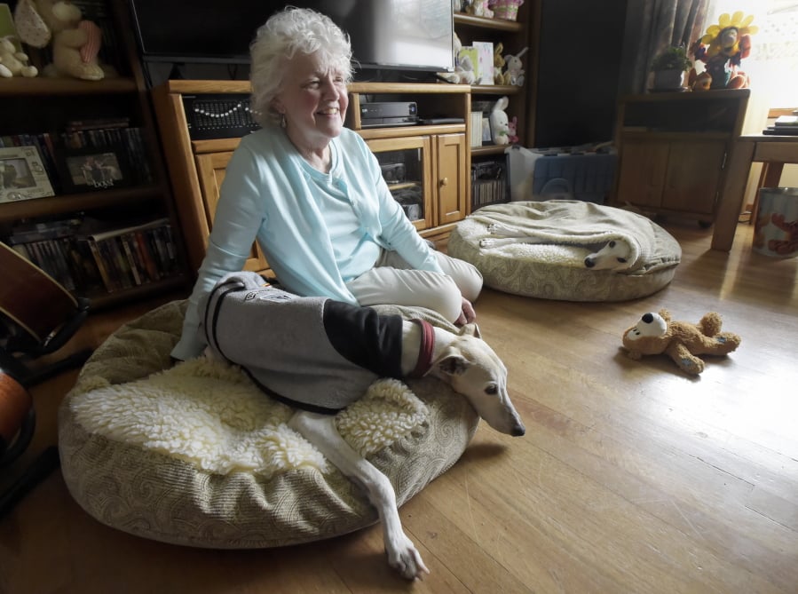 Jacqueline Barrington, a retired teacher sits with her dogs, Dustee and Jackson, in Corvallis, Ore. Barrington, who does a lot of the READ dog events at schools and the libraries, has a whippet she thinks is the longest serving reading dog ever. Dustee is older now and is expected to retire at the end of the year. Jackson, on the pillow to the right, will be taking over as a READ dog in January.