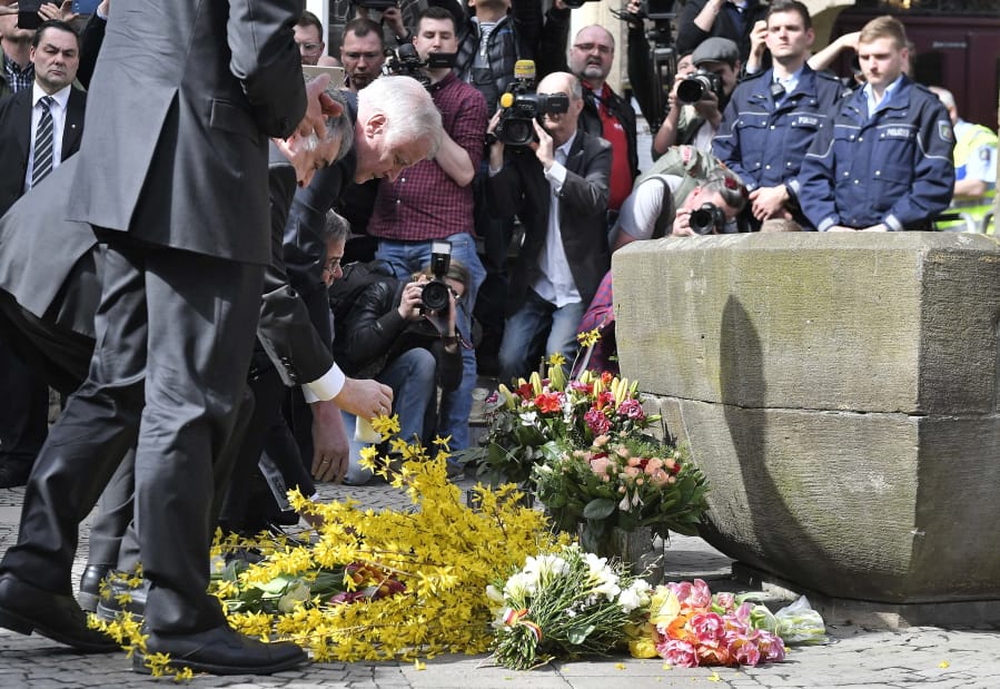 German interior minister Horst Seehofer places flowers at the place in Muenster, Germany, on Sunday, where a vehicle crashed into a crowd yesterday. A van crashed into people drinking outside a popular bar Saturday in the German city of Muenster, killing two people and injuring 20 others before the driver of the vehicle shot and killed himself inside it, police said.