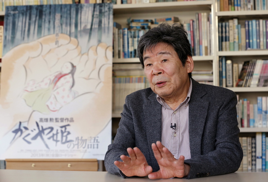 In this Feb. 12, 2015 photo, Japanese animated film director Isao Takahata speaks about his latest film “The Tale of The Princess Kaguya” with its poster during an interview at his office, Studio Ghibli, in suburban Tokyo. Takahata, co-founder of the prestigious Japanese animator Studio Ghibli that stuck to a hand-drawn “manga” look in the face of digital filmmaking, has died. He was 82. Takahata, who directed “Grave of the Fireflies,” a tragic tale about wartime childhood, died Thursday, April 5, 2018, of lung cancer at a Tokyo hospital, according to a studio statement.