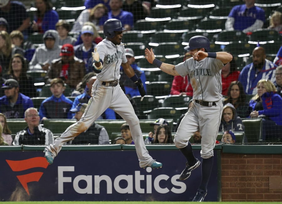 Seattle Mariners Dee Gordon, left, and Andrew Romine (7) celebrate after scoring on a double by Jean Segura during the ninth inning of a baseball game against the Texas Rangers on Friday, April 20, 2018, in Arlington, Texas. (AP Photo/Richard W.
