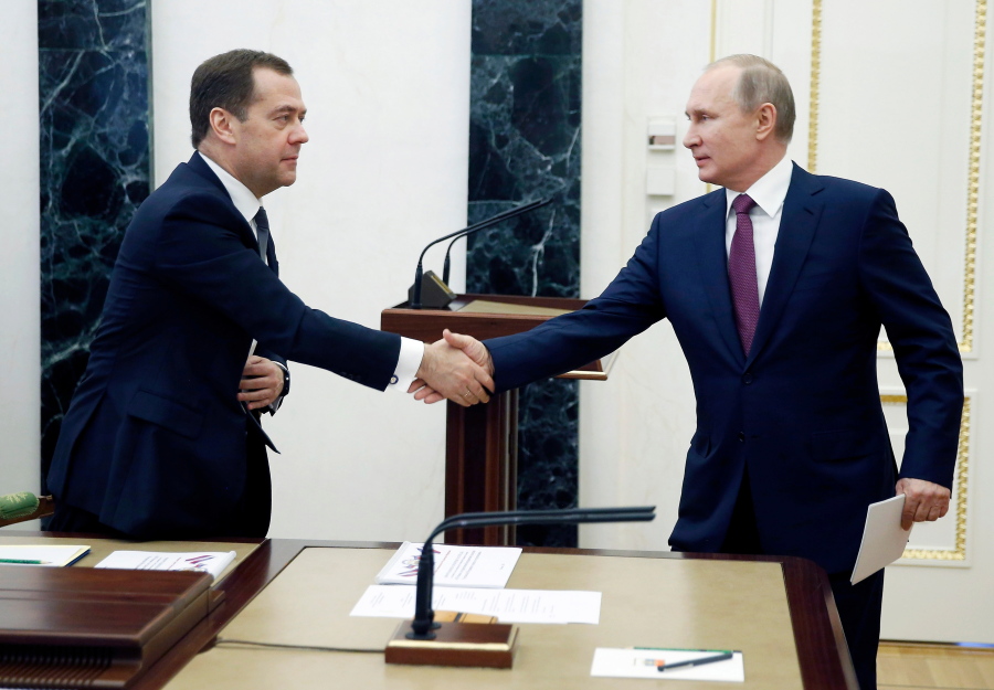 Russian President Vladimir Putin, right, shakes hands with Russian Prime Minister Dmitry Medvedev as he arrives to attend a Security Council meeting in Moscow, Russia, Friday, April 6, 2018. The meeting focused on border protection.