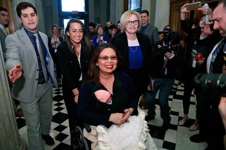 Sen. Tammy Duckworth, D-Ill., carries her baby Maile Pearl Bowlsbey as she heads to the Senate floor to vote, with Sen. Claire McCaskill, D-Mo., at right, on Capitol Hill, Thursday, April 19, 2018 in Washington.