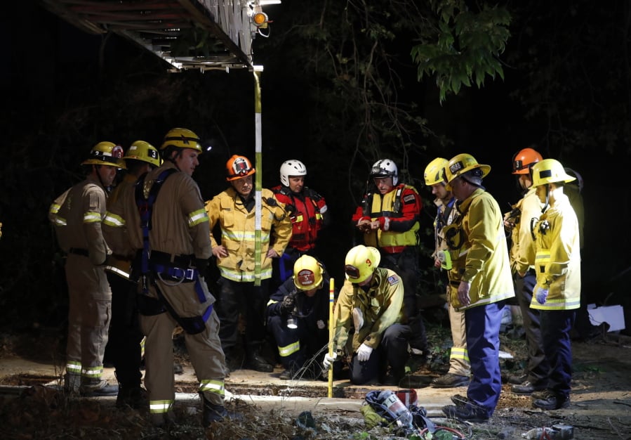 Firefighters search for a 13-year-old boy in a hole near the LA River at the 134 and 5 Freeway interchange Sunday, April 1, 2018, in Los Angeles. The 13-year-old boy, who fell into a drainage pipe during a family Easter outing at a Los Angeles park, was found alive early Monday following a frantic, 12-hour search of the underground system, authorities said.