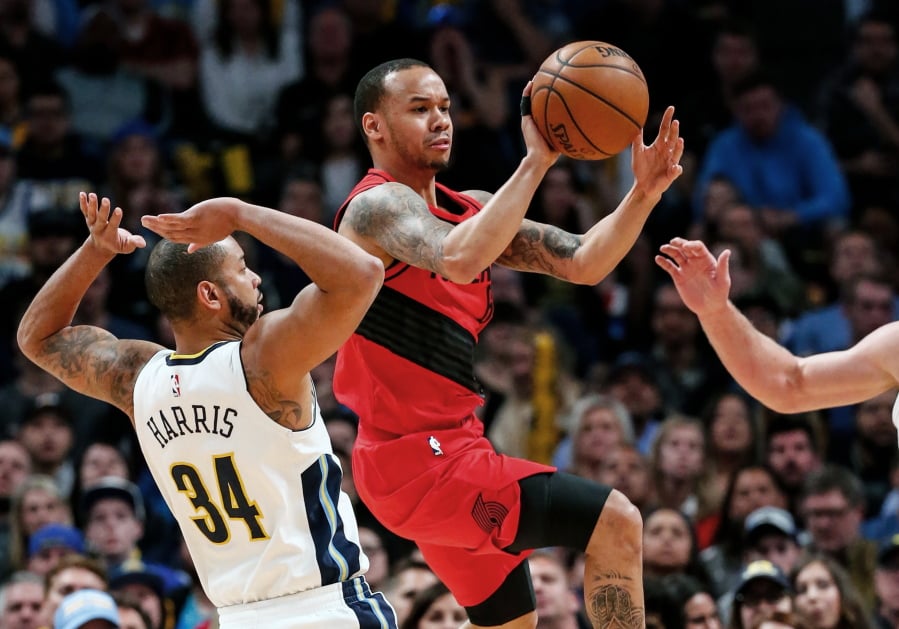 Portland Trail Blazers guard Shabazz Napier, center, passes around Denver Nuggets guard Devin Harris (34) during the first quarter of an NBA basketball game Monday, April 9, 2018, in Denver.