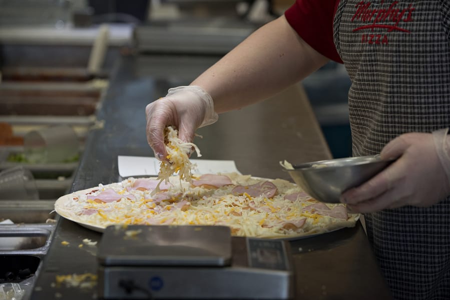 Tayler Smith of Papa Murphy’s sprinkles cheese while creating a pizza in March 2016 at Papa Murphy’s on East Mill Plain Boulevard.