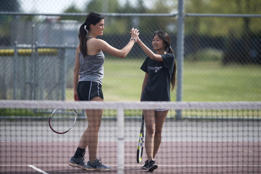 Union’s Nicole Knudtson, left, high fives doubles partner Yannie Li during a match against Camas this season. Knudtson’s promising tennis career has been limited by a bone condition in her left ankle. But that hasn’t stopped her from being one of the state’s top doubles players.