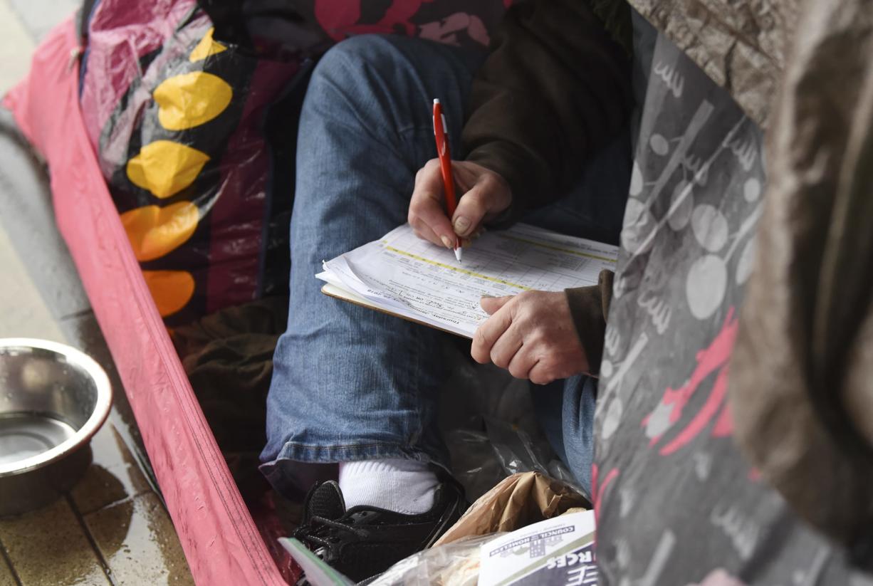 A homeless woman fills out a form while in her tent under a bridge on Esther Street in January, when an annual Point in Time street count gathered information on homeless people in the county.