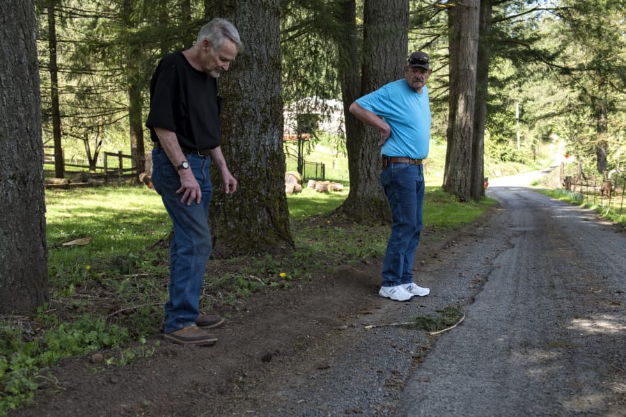 Richard Landis, left, and Bernie Ritter discuss damage to their road, Northeast 312th Avenue, and the recent efforts by Clark County to repair it. The residents say their one-lane road is getting perpetually damaged by the increased traffic relating to a new subdivision being built at the end of the road.