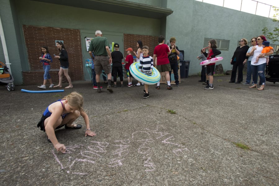 The Friends of Crown Park Pool held a “pool party without the pool” to try to save the Crown Park swimming pool, which is scheduled for demolition this fall. Elina Sams, 8, of Camas, and other kids wrote messages in chalk in support of the pool during the party.