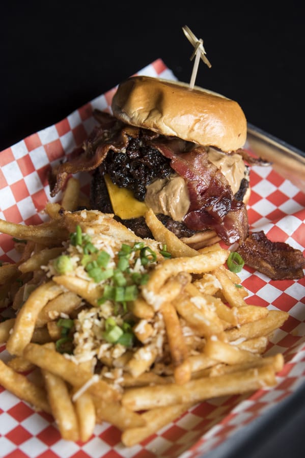 The peanut butter burger served with bacon jam, bacon and American cheese, and a side of garlic fries at Playmakers Bar & Grill in Battle Ground.