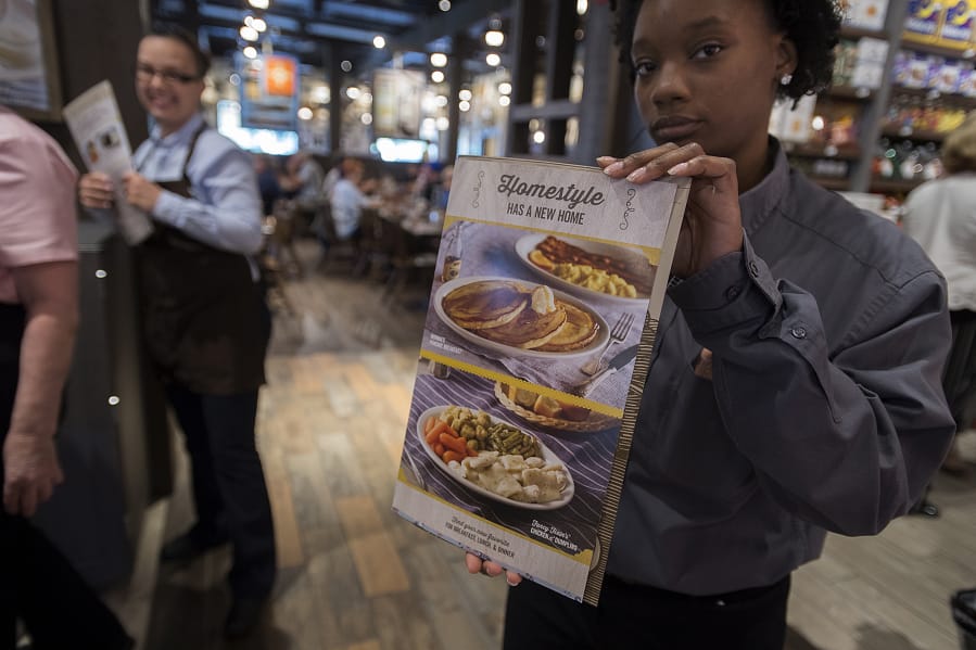 Operations trainer Nicole Brown displays a menu at the entrance to the dining area at Cracker Barrel Old Country Store. The store opened Monday and seats about 180.
