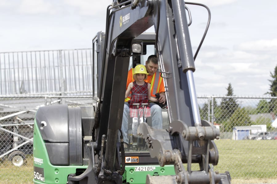 Six-year-old Liah Hansen-Bruen tries her hand at operating an excavator with help from Frank Lott on Sunday afternoon at Dozer Day.