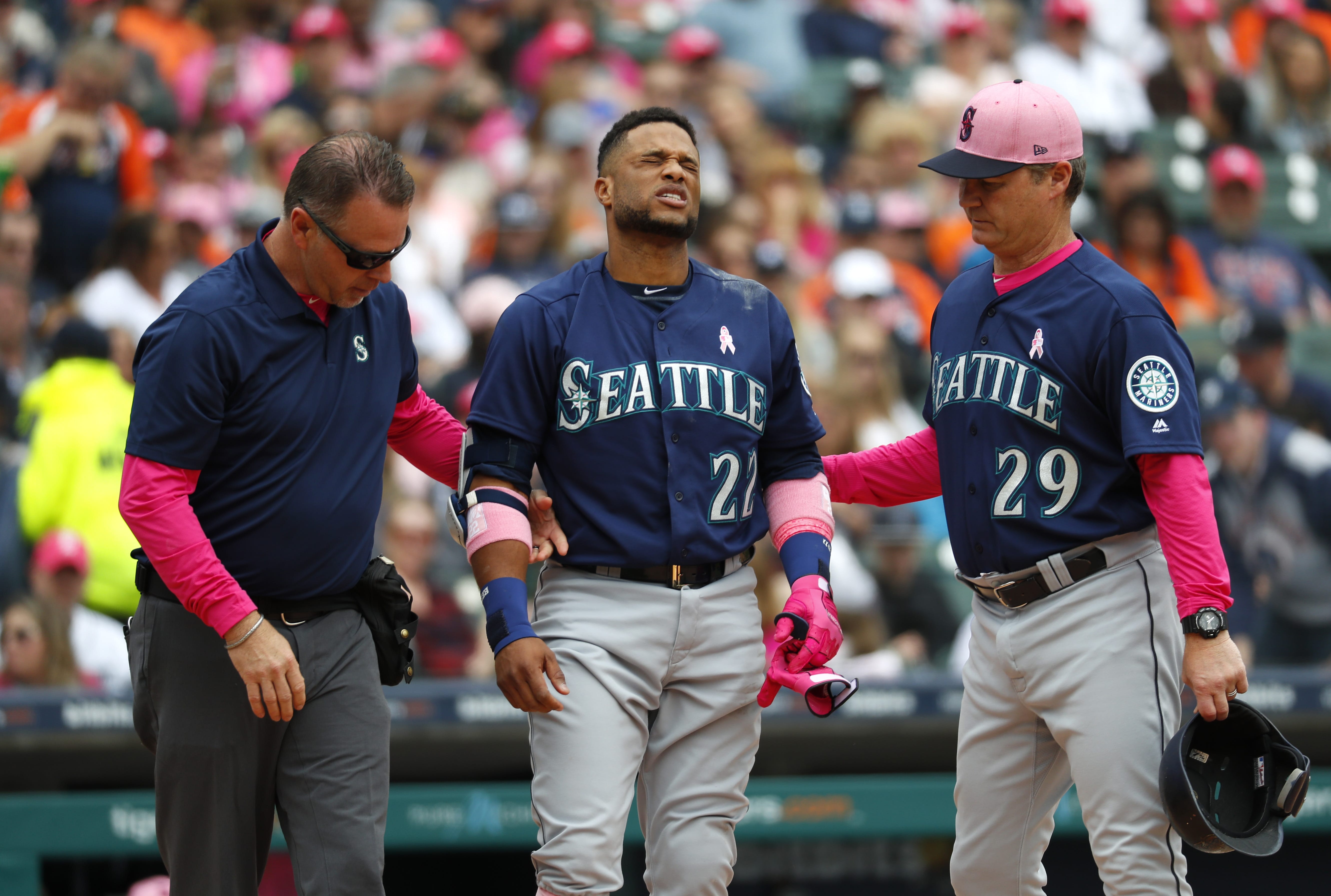 Seattle Mariners' Robinson Cano (22) grimaces while being attended to by trainer Rob Nodine, left, and manager Scott Servais (29) after being hit in the hand by a Detroit Tigers' Blaine Hardy pitch in the third inning of a baseball game in Detroit, Sunday, May 13, 2018. Cano left the game.